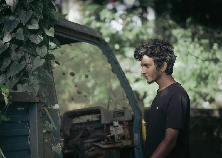 a man that is standing in front of a truck, an album cover, pexels contest winner, hyperrealism, many overgrown scrap cars, still from a terence malik film, portrait of a young italian male, gardening