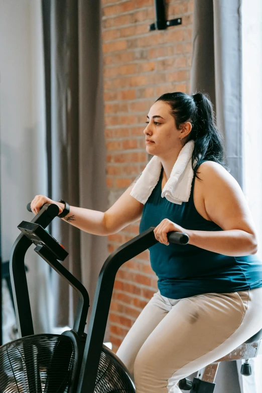 a woman is sitting on an exercise bike, pexels contest winner, figuration libre, curvy build, looking sad, low quality photo, trapped on a hedonic treadmill