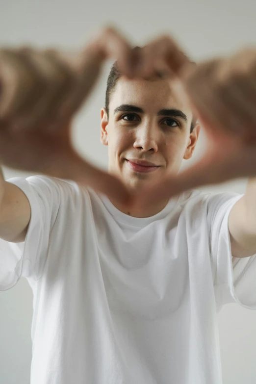 a man making a heart with his hands, an album cover, inspired by Jean Malouel, pexels contest winner, clean shaven wide face, young spanish man, 15081959 21121991 01012000 4k, teenager