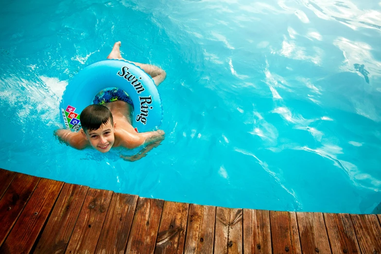 a young boy swimming in a pool with an inflatable raft, by Sebastian Spreng, pexels contest winner, thumbnail, smooth skin, brown, 1 2 9 7