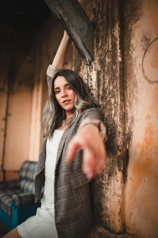 a woman leaning against a wall with a knife in her hand, a picture, trending on pexels, pointing at the camera, dilapidated look, shot with premium dslr camera, hands reaching for her