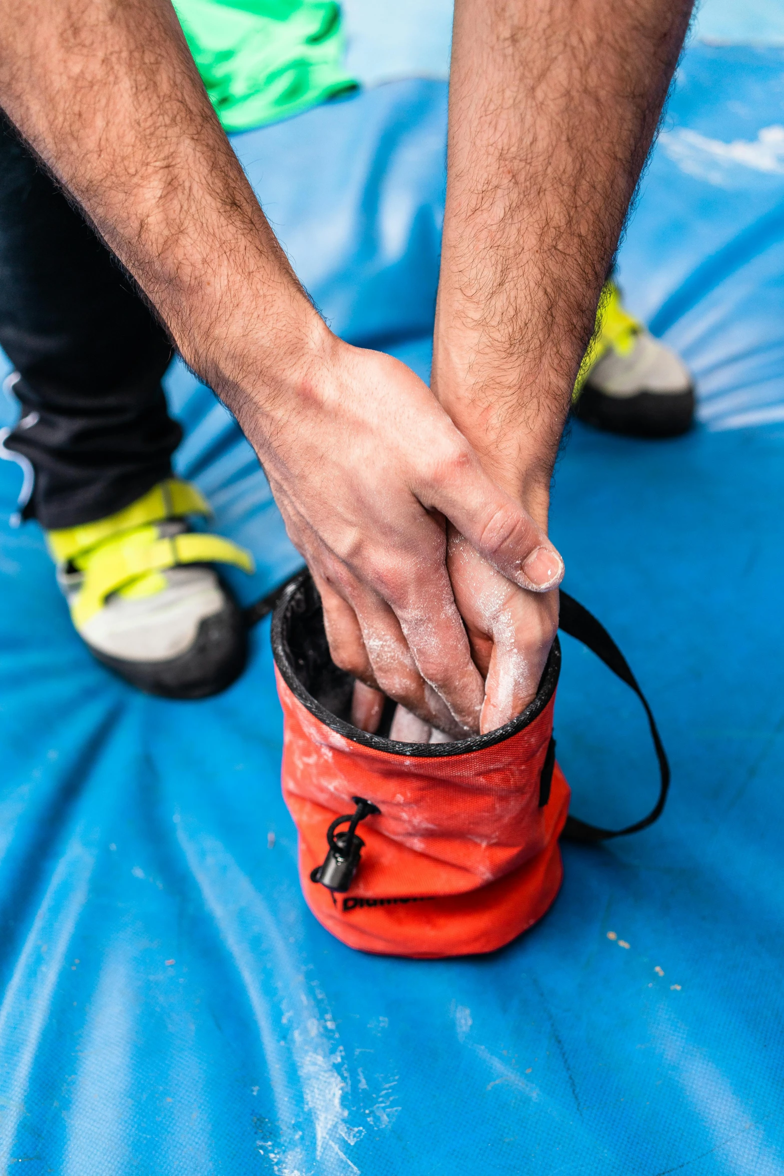 a person holding a red bag on top of a blue tarp, by Francis Helps, dribble, rock climbing, fingerless gloves, hydration, thumbnail