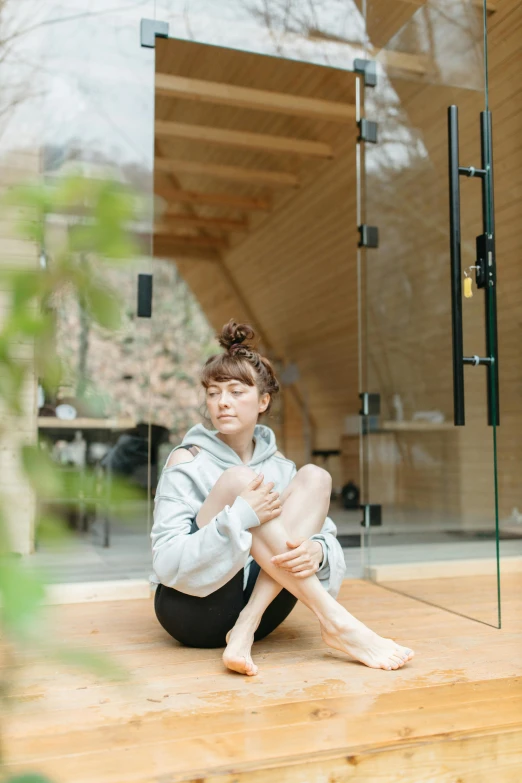 a woman sitting on the ground in front of a glass door, unsplash, shin hanga, cottagecore!! fitness body, architect studio, wearing a tracksuit, 奈良美智