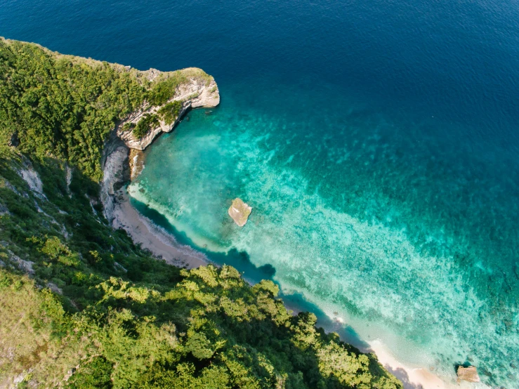 a large body of water next to a lush green hillside, pexels contest winner, crystal clear sea, conde nast traveler photo, aerial footage, trees and cliffs