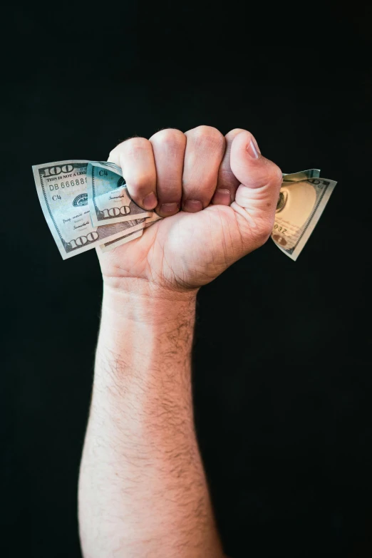 a man holding a bunch of money in his hand, a colorized photo, pexels contest winner, clenched fist, split in half, smol, violently fist fighting