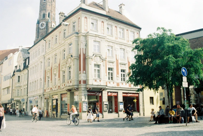 a group of people walking down a street next to tall buildings, a photo, danube school, town hall, movie filmstill, square, house's and shops and buildings
