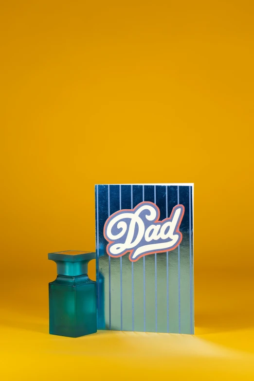 a bottle of cologne next to a card with the word dad on it, an album cover, by Doug Ohlson, dynamic pearlescent teal light, mini model, alternate angle, ditka