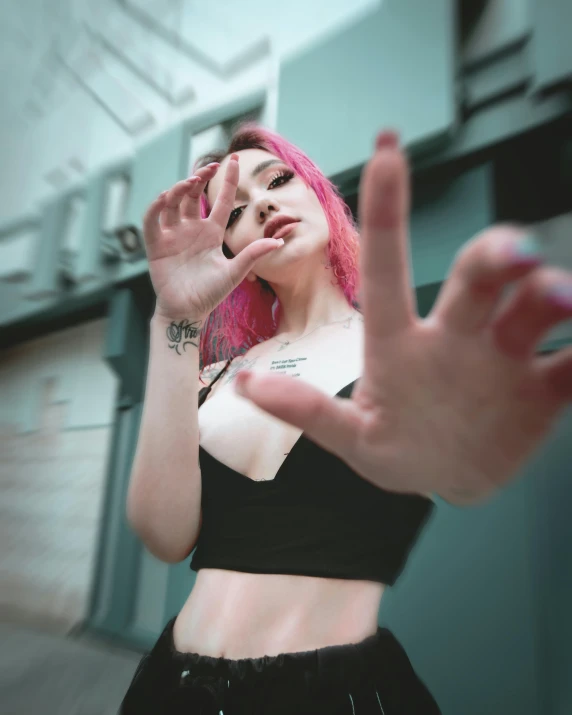 a woman with pink hair wearing a black top, a photo, inspired by Elsa Bleda, trending on pexels, hand gesture, queer woman, wearing bra, perspective shot