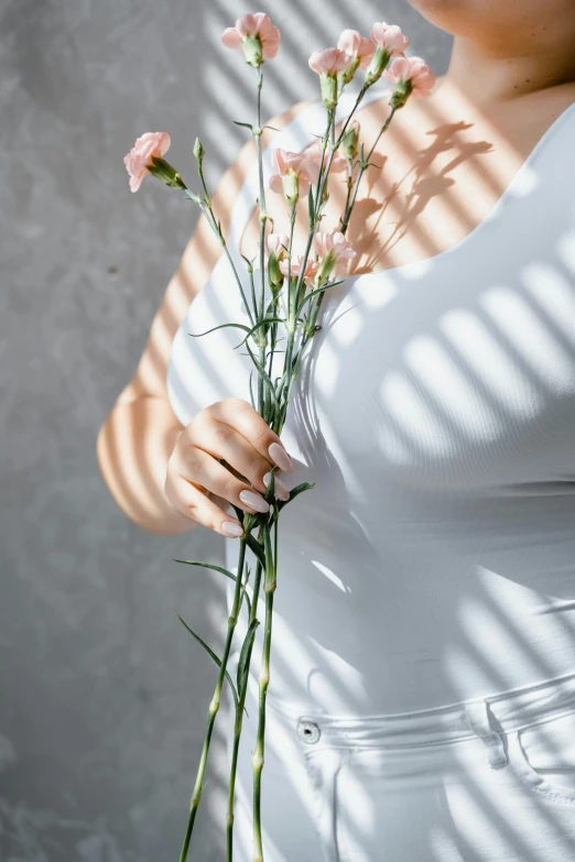 a woman holding a bunch of pink flowers, a marble sculpture, inspired by Robert Mapplethorpe, unsplash, diffuse natural sun lights, wearing white camisole, shadow and light, high-body detail