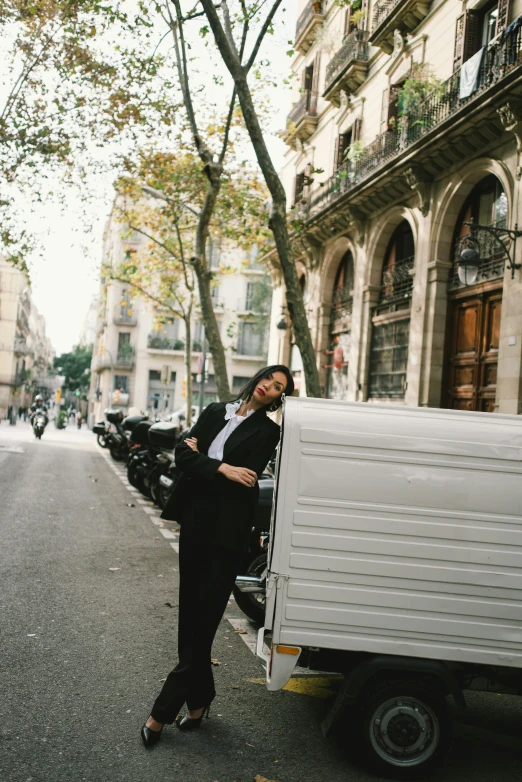 a woman standing next to a truck on a city street, by Nina Hamnett, trending on unsplash, happening, barcelona, black suit pants, milkman, autum