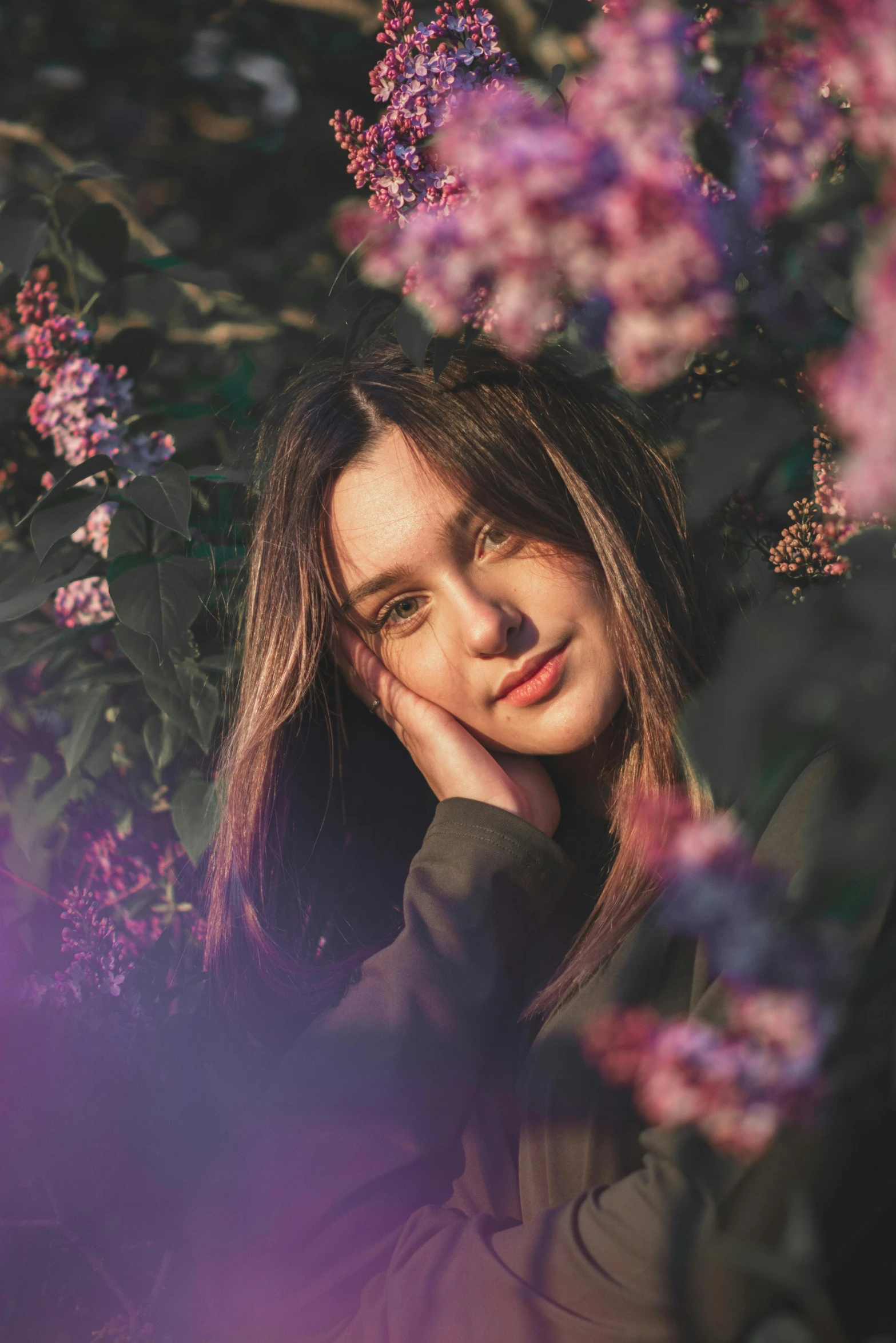 a woman standing in front of purple flowers, inspired by Elsa Bleda, trending on pexels, handsome girl, portrait sophie mudd, twitch streamer, girl with dark brown hair