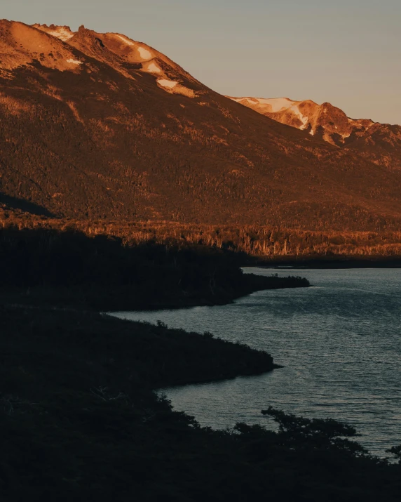 a body of water with a mountain in the background, an album cover, inspired by Elsa Bleda, unsplash contest winner, filtered evening light, patagonian, view of forest, ignant