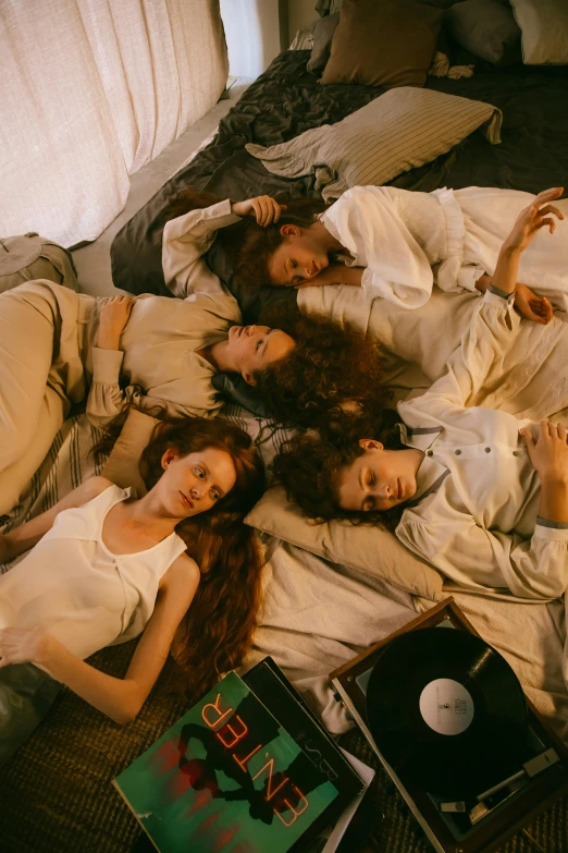 a group of people laying on top of a bed, an album cover, inspired by Nan Goldin, trending on pexels, renaissance, ( redhead, cute girls, valentin serov style, white clothes