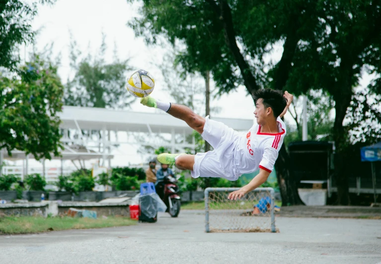 a man kicking a soccer ball in the air, by Bernardino Mei, pexels contest winner, realism, asian male, 15081959 21121991 01012000 4k, on the concrete ground, square