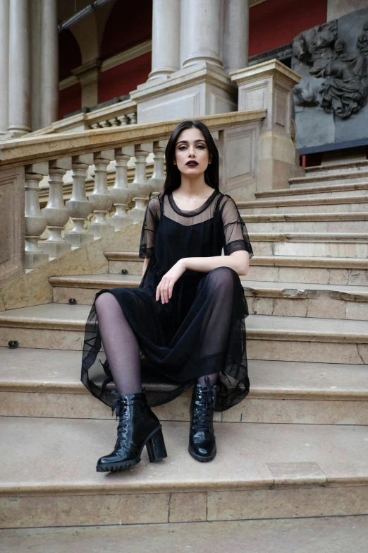 a woman sitting on the steps of a building, inspired by Elsa Bleda, pexels contest winner, gothic art, wearing a gothic dress, black furniture, dua lipa, see - through