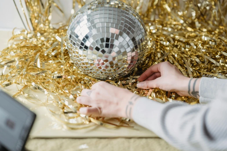 a close up of a person holding a disco ball, by Julia Pishtar, process art, gold decorations, filling the frame, holiday, 1 9 2 0 s cloth