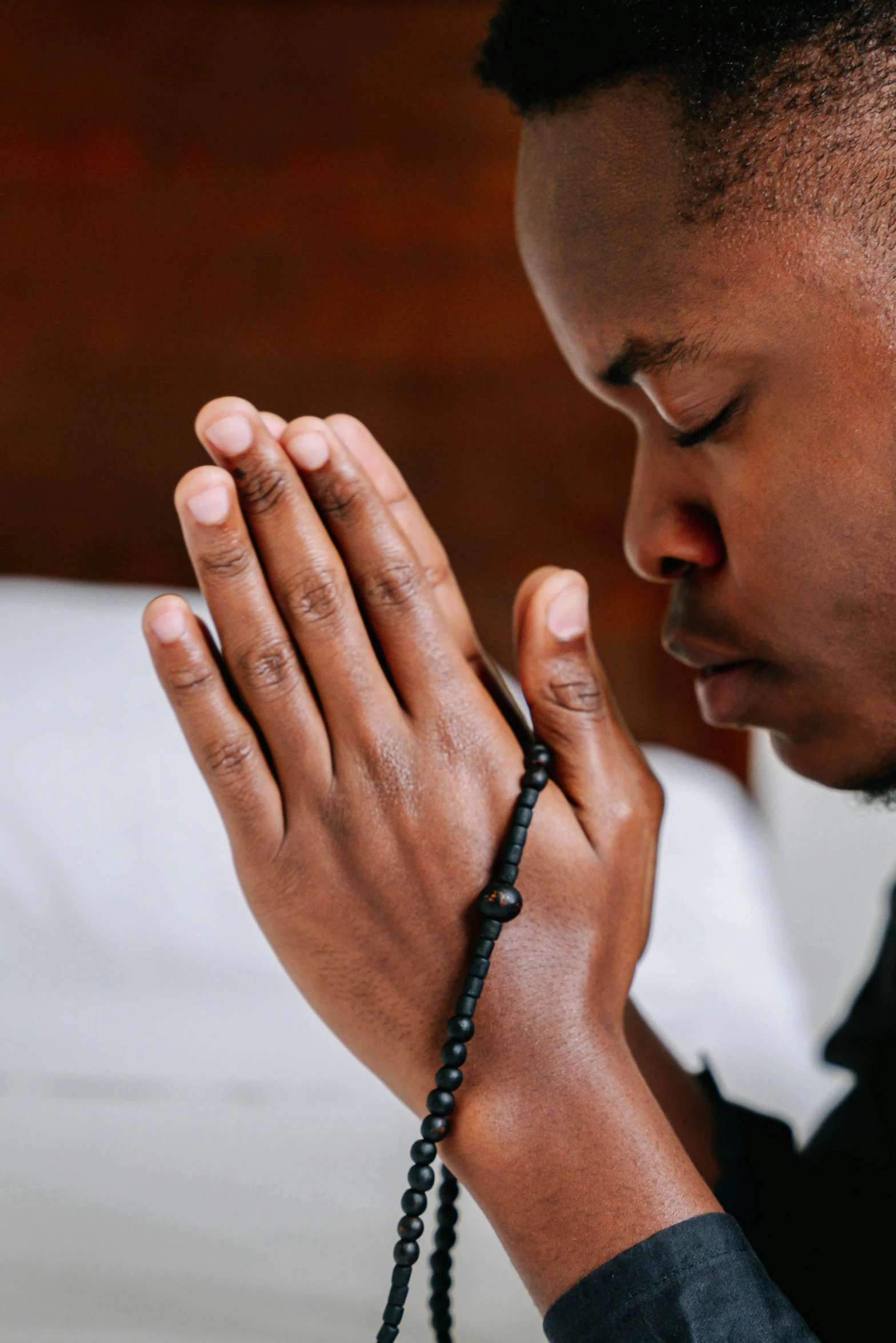 a man is praying while sitting on a bed, trending on unsplash, hurufiyya, african iconography, profile image, multiple stories, closed hands