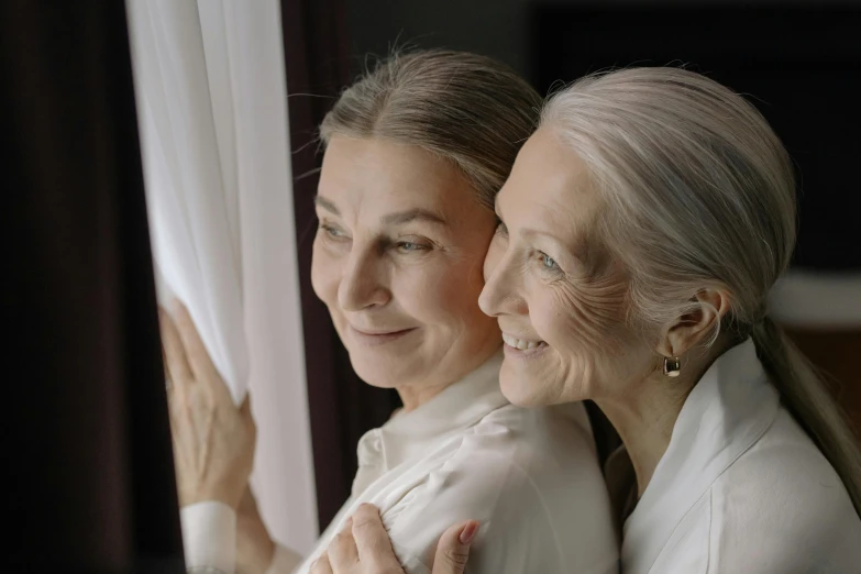 two older women looking out of a window, pexels contest winner, photorealism, silver，ivory, holding each other, beauty shot, looking straight