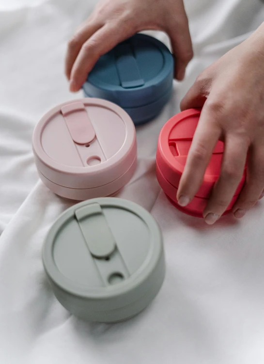 a person reaching for a plastic container on a bed, trending on unsplash, mauve and cinnabar and cyan, silicone cover, coffee cups, detailed product photo