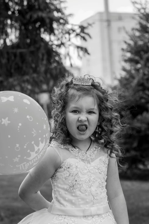 a black and white photo of a little girl holding a balloon, by Lucia Peka, pexels contest winner, happening, wearing tiara, an angry, curls, mischievous!!!