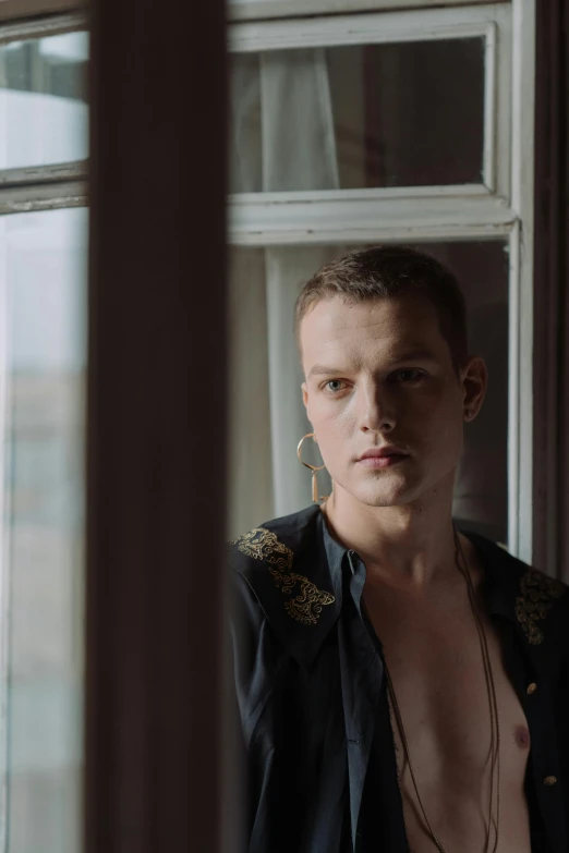 a shirtless man standing in front of a window, an album cover, unsplash, renaissance, beautiful androgynous prince, vitalik buterin, huge earrings and queer make up, pawel rebisz
