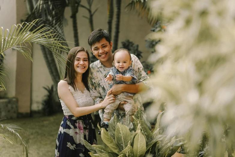 a man and woman holding a baby in a garden, pexels contest winner, manila, avatar image, background image, portrait shot 8 k