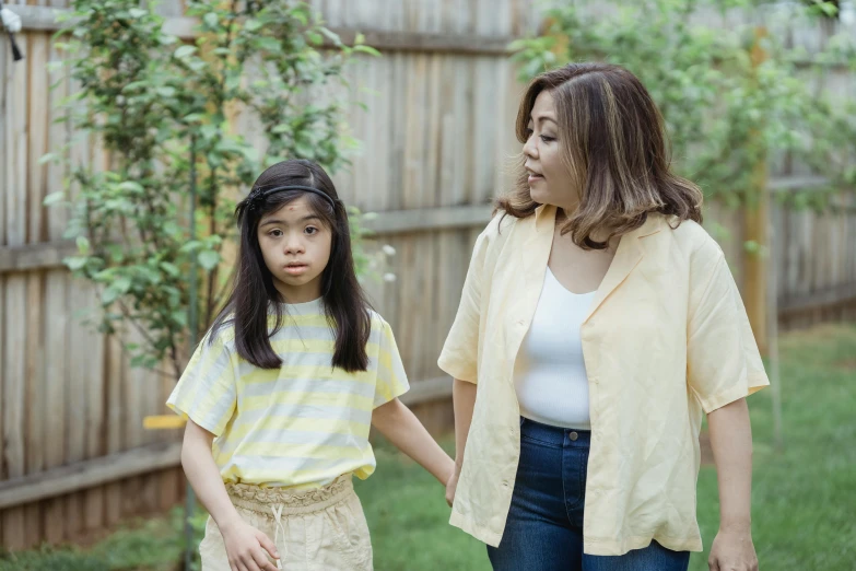 a woman standing next to a little girl in a yard, inspired by Ruth Jên, pexels, dau-al-set, yellow clothes, disappointed, wearing a light shirt, asian woman