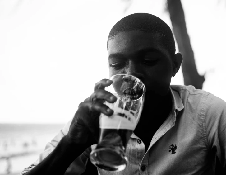 a black and white photo of a man drinking a beer, by Dean Ellis, pexels, kehinde wiley, yung lean, seaside, aged 13