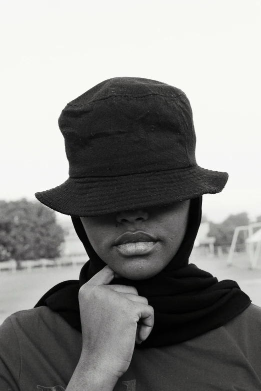 a black and white photo of a woman wearing a hat, a black and white photo, unsplash, visual art, somali woman, tomboy, taken in the late 2000s, face covered