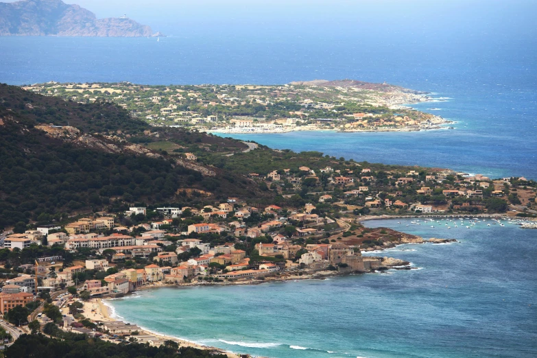 a large body of water next to a lush green hillside, a photo, traditional corsican, soft-sanded coastlines, surrounding the city, slide show