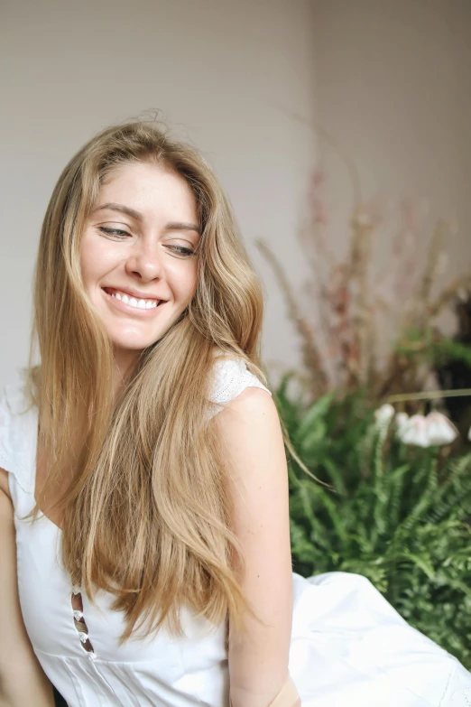 a beautiful young woman sitting on top of a bed, trending on pexels, renaissance, extra-light natural blonde hair, turning her head and smiling, covered in plants, attractive brown hair woman