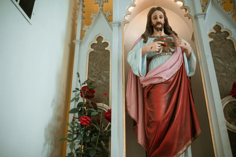 a statue of jesus holding a cross in a church, a statue, by Meredith Dillman, pexels, wearing an ornate outfit, red fluid on walls of the church, a brightly coloured, a handsome