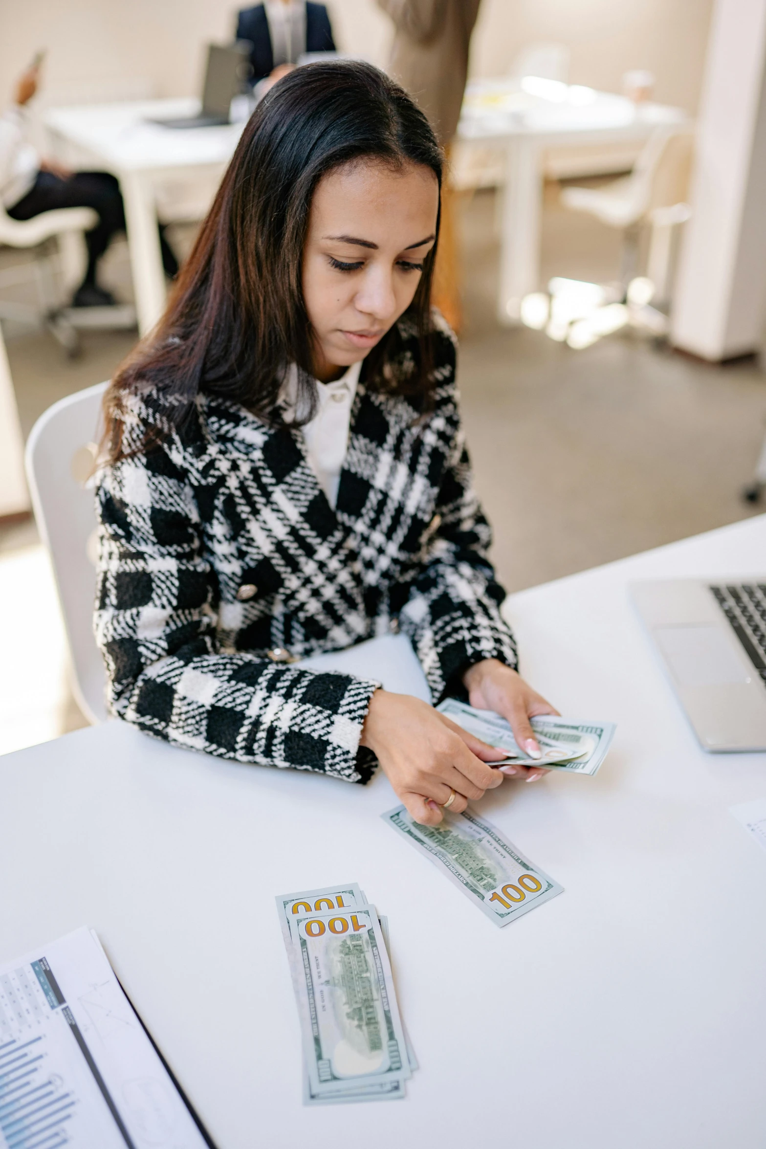 a woman sitting at a table with money and a laptop, white and teal garment, thumbnail, - 9