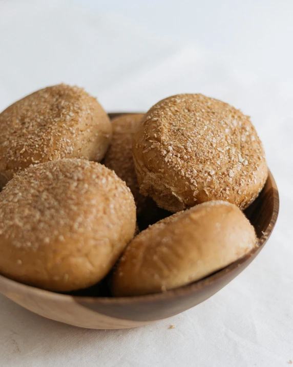 a bowl filled with doughnuts sitting on top of a table, bread, heavy grain, thumbnail, sandstone