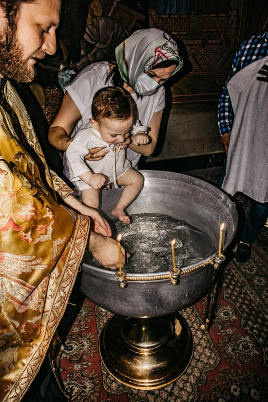 a man in a priest's robes washing a baby, by Alexander Fedosav, trending on unsplash, in orthodox church, at a birthday party, inside the sepulchre, cauldrons