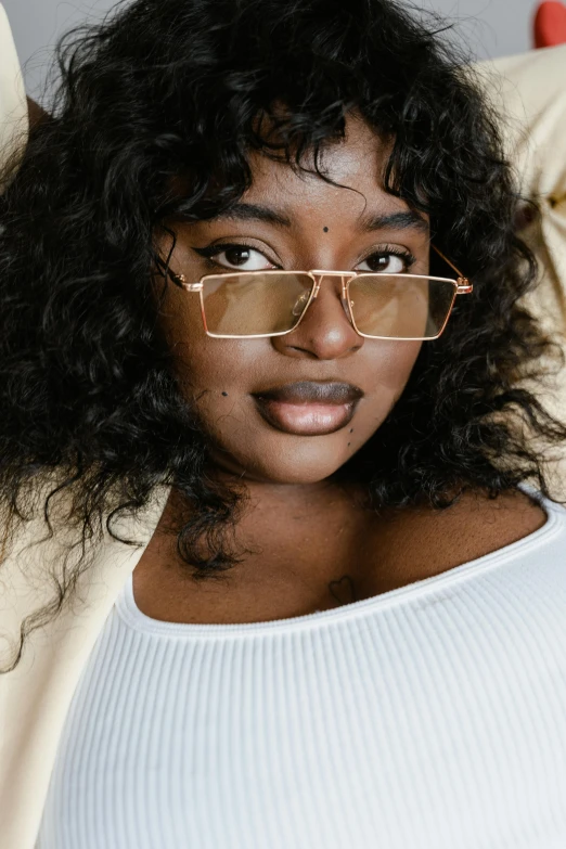 a woman with glasses sitting on a couch, by Carey Morris, trending on pexels, imaan hammam, gold framed, square face, plus size woman