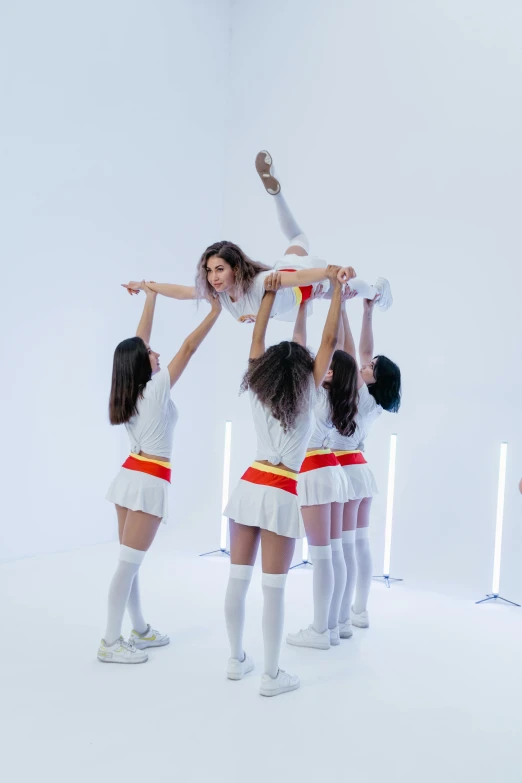 a group of young women standing on top of each other, an album cover, inspired by David LaChapelle, trending on pexels, arabesque, white uniform, ana de armas, toy commercial photo, performing