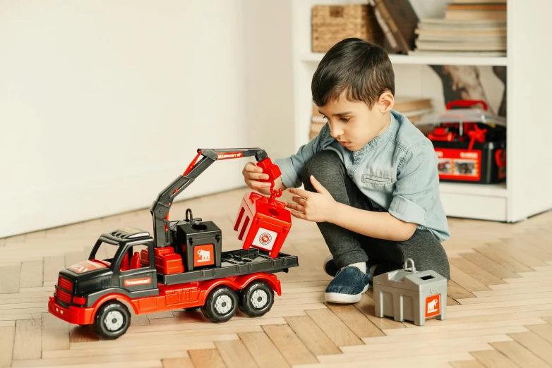 a young boy playing with a toy truck, pexels contest winner, red and black colour scheme, anthracite, official product photo, with mechanical arms that fix it