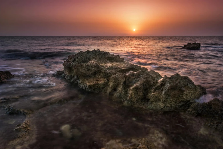 a sunset over the ocean with rocks in the foreground, pexels contest winner, red sea, coral, cyprus, brown