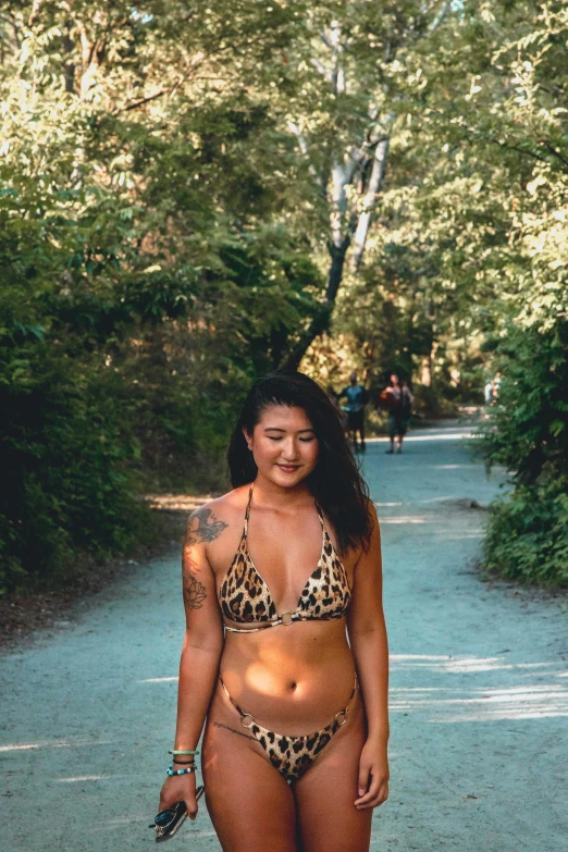 a woman in a bikini walking down a dirt road, of taiwanese girl with tattoos, lush surroundings, confidence, 2019 trending photo