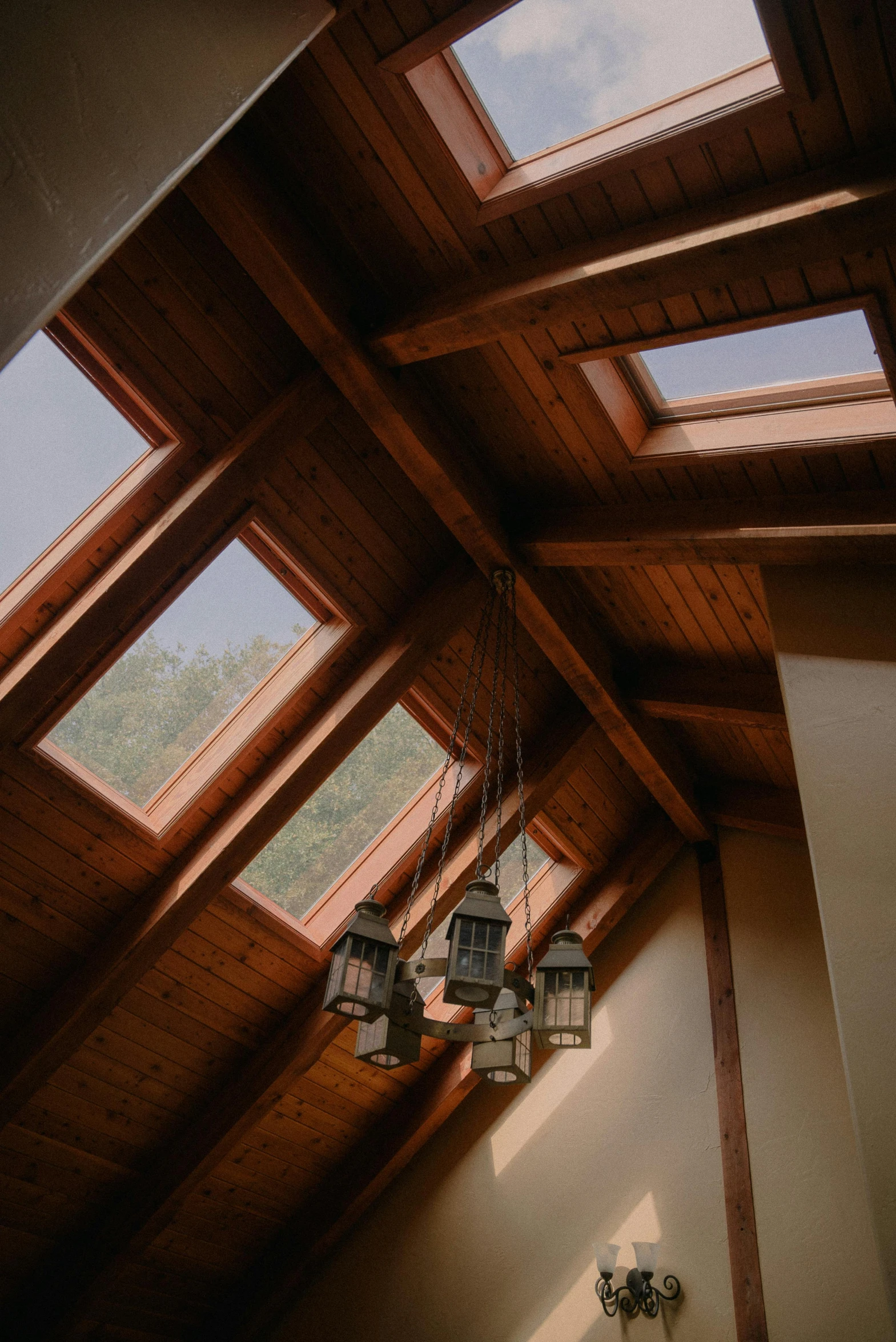 a room filled with lots of windows and a chandelier, pexels, light and space, peaked wooden roofs, skylights, cabin lights, high quality image