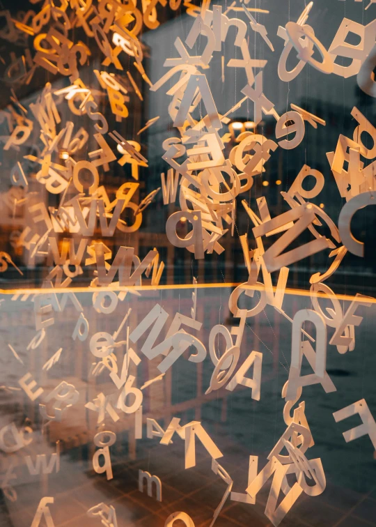 a window that has a bunch of letters on it, by Matija Jama, trending on unsplash, letterism, golden dappled dynamic lighting, abstract sculpture, 15081959 21121991 01012000 4k, educational