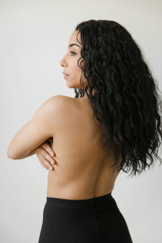 a woman standing with her back to the camera, by Sara Saftleven, black curly hair, photoshoot for skincare brand, bare chest, kailee mandel