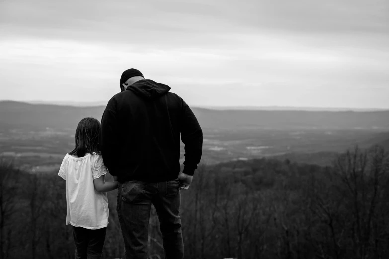 a man and a little girl standing on top of a hill, a black and white photo, pexels, visual art, william penn state forest, overlooking, father, instagram post