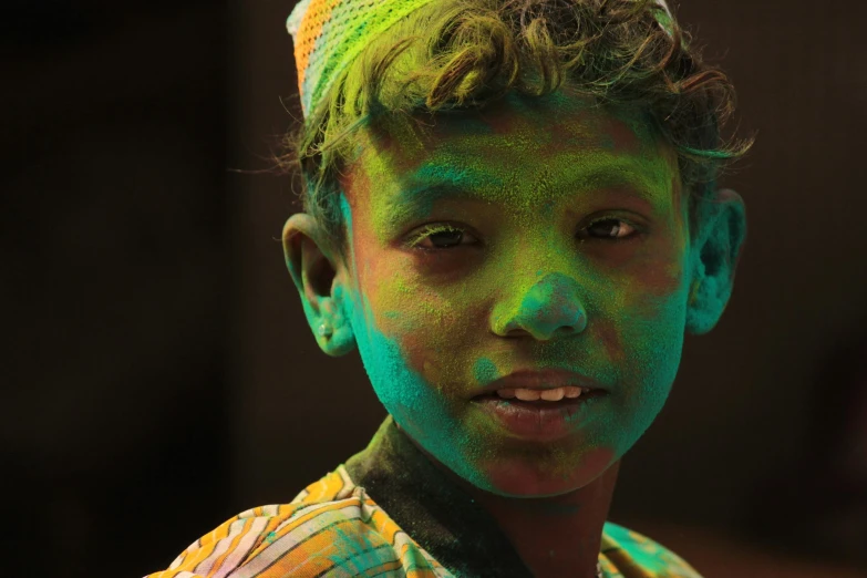 a young boy with green paint on his face, pexels contest winner, hurufiyya, glowing hue of teal, with colourful intricate, young commoner, low colour