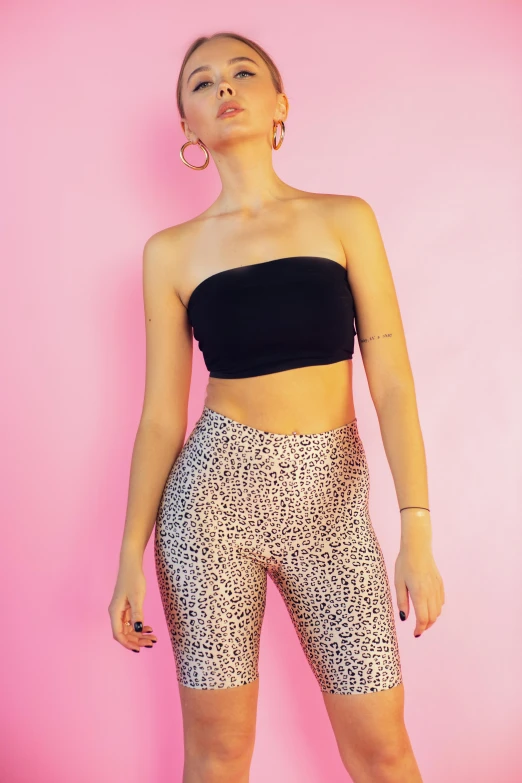 a woman in a black top and leopard print shorts, an album cover, by Nina Hamnett, trending on pexels, leggins, pink halter top, y2k aesthetic, basic background