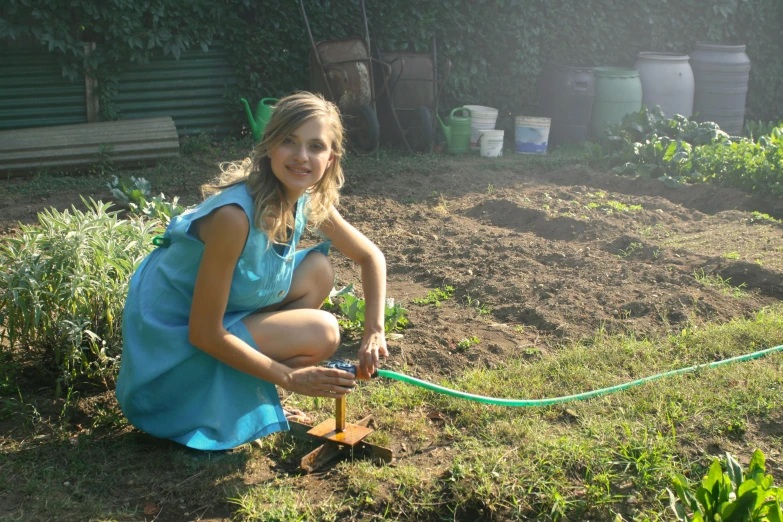 a woman that is kneeling down with a hose, inspired by Elsa Beskow, pexels contest winner, land art, aged 13, low quality photo, using a spade, handsome girl