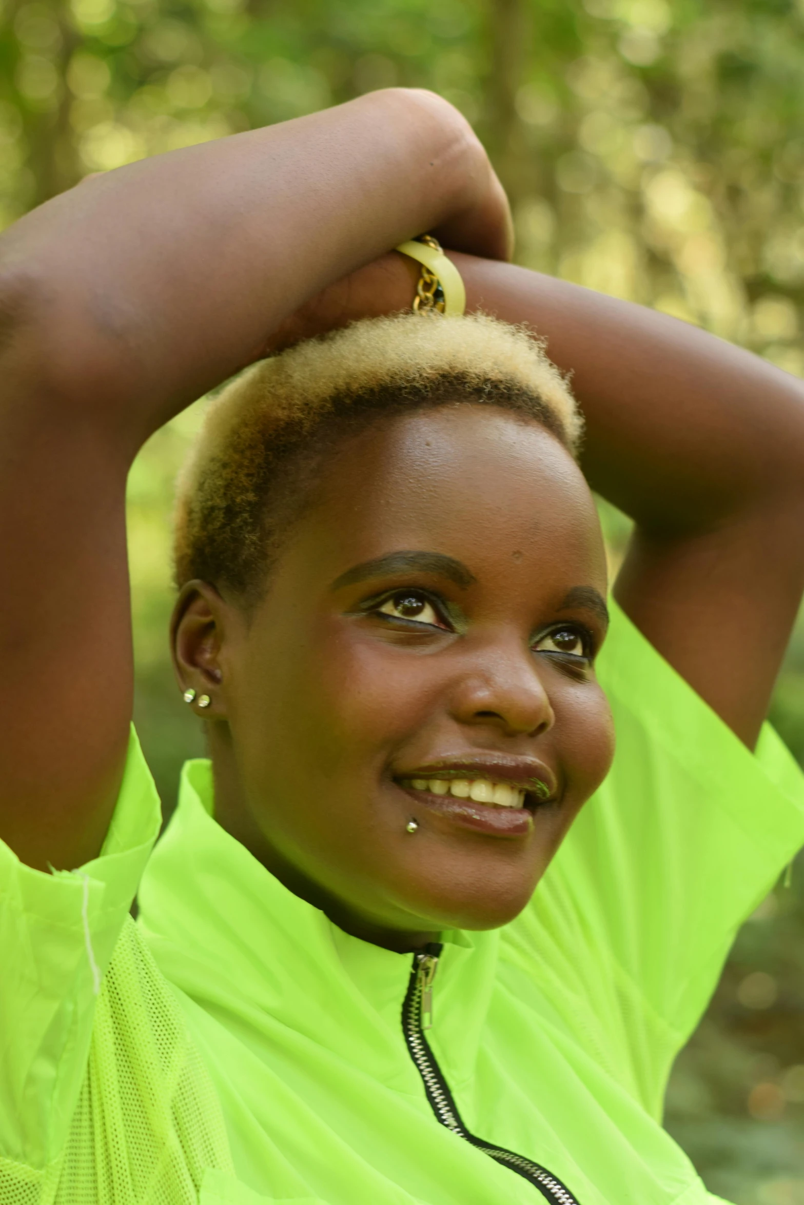 a woman in a green shirt posing for a picture, by Ingrida Kadaka, hurufiyya, gold hair, clean shaven, no crop, celebrating