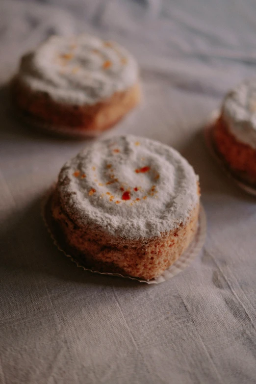 a couple of cookies sitting on top of a table, orange and white, covered in white flour, detailed product image, spicy