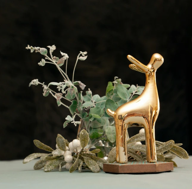 a gold deer figurine sitting on top of a table, inspired by Rudolph F. Ingerle, unsplash contest winner, new sculpture, on a wooden plate, flora and fauna, glossy finish, organic ornament